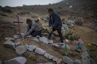 Siblings Julia and Jorge Lopez decorate the burial site of their mother, who recently died from the new coronavirus, at a public cemetery in Lima, Peru, Friday, May 22, 2020. Despite strict measures to control the virus, this South American nation of 32 million has become one of the countries worst hit by the disease. (AP Photo/Rodrigo Abd)