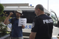 A protester carries a placard that reads: "suitcase, on the train to Moscow," as expelled Russian diplomatic staff arrive at Sofia's airport, Bulgaria, Sunday, July 3 2022. Two Russian airplanes were set to depart Bulgaria on Sunday with scores of Russian diplomatic staff and their families amid a mass expulsion that has sent tensions soaring between the historically close nations, a Russian diplomat said. (AP Photo/Valentina Petrova)