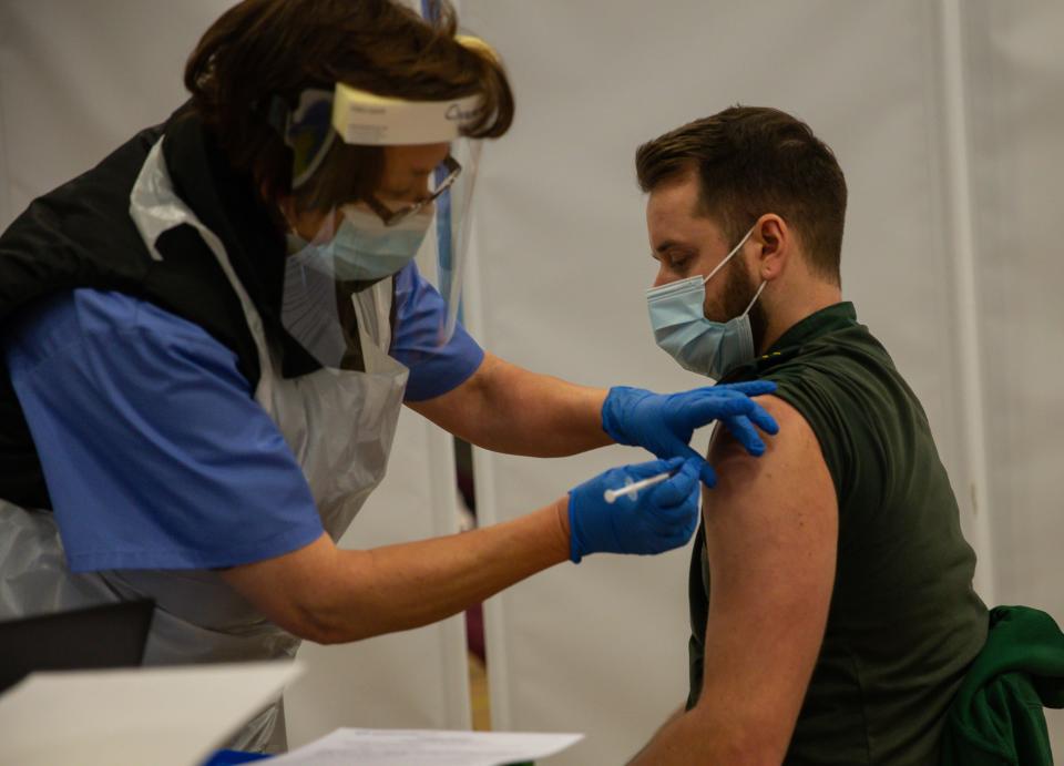 CWMBRAN, WALES - DECEMBER 29:  A member of the Welsh Ambulance Trust receives his first dose of the Pfizer/BioNTech vaccine in the waiting area for any adverse reactions on December 29, 2020 in Cwmbran, Wales. Various locations across United Kingdom were designated as covid-19 vaccine hubs. NHS staff, over-80s, will be among the first to receive the Pfizer/BioNTech vaccine, which recently received approval from the country's health authorities. It is anticipated that the Oxford University Vaccine will be approved within the next few days. (Photo by Huw Fairclough/Getty Images)