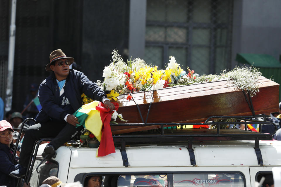 A man sits on top of a van carrying a coffin that contain the remains of a person killed in clashes between supporters of former President Evo Morales and security forces, in a funeral procession into La Paz, Bolivia, Thursday, Nov. 21, 2019. Mourners and anti-government demonstrators marched to La Paz with the coffins of some of the at least eight people killed Tuesday when security forces cleared a blockade of a fuel plant by Morales' backers in the city of El Alto. (AP Photo/Natacha Pisarenko)