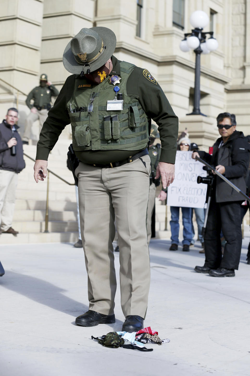 In this Monday, Jan. 4, 2021, photo a Wyoming State Trooper stomps out a pile of burning masks during the Free Wyoming rally against Wyoming Gov. Mark Gordon and the face mask mandates outside the Capitol in downtown Cheyenne, Wyo. Gov. Gordon quietly mobilized dozens of National Guard troops in case of any violence at the state Capitol in Cheyenne, in January. The deployment came to light Friday, March 5, 2021, after an Associated Press inquiry after the Jan. 6 riot at the U.S. Capitol, which left five dead. (Michael Cummo/The Wyoming Tribune Eagle via AP)