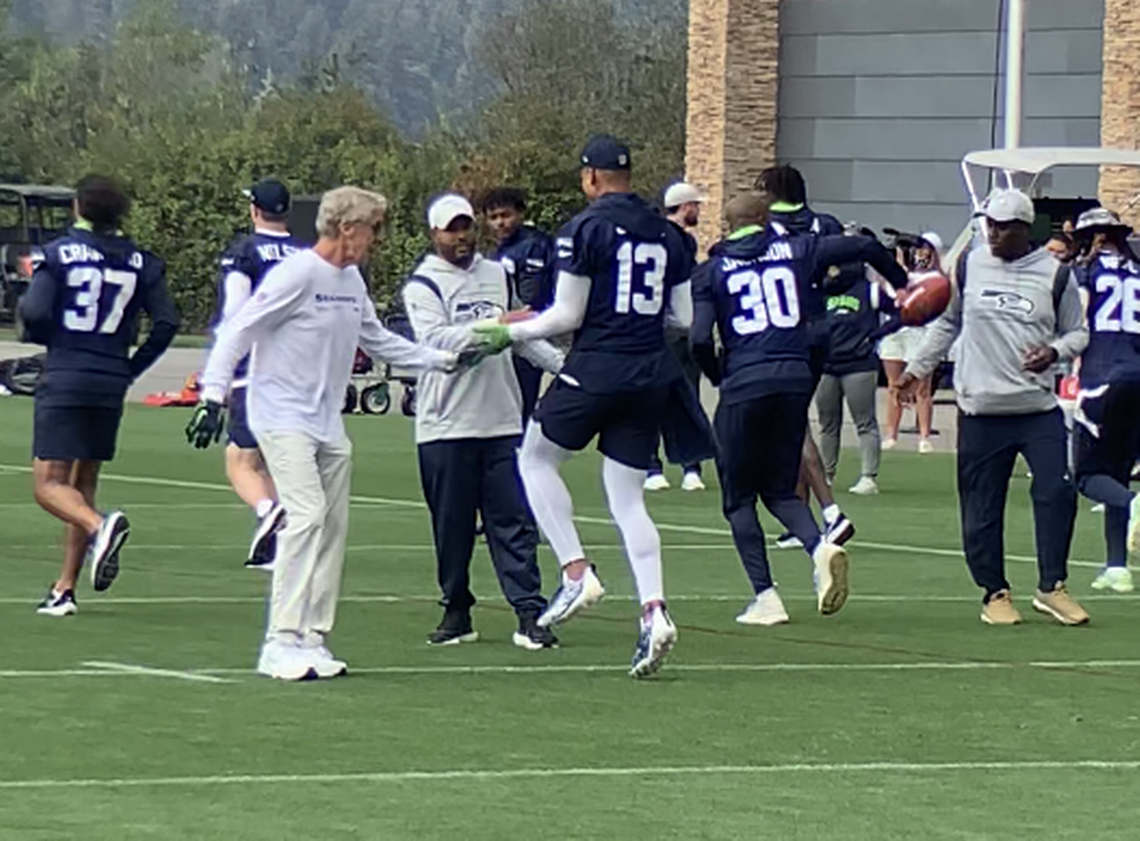 Coach Pete Carroll (left, in white) greets Seahawks safety Josh Jones (13) during the team’s warmups for practice Wednesday, Sept. 14, 2022, at the Virginia Mason Athletic Center in Renton.