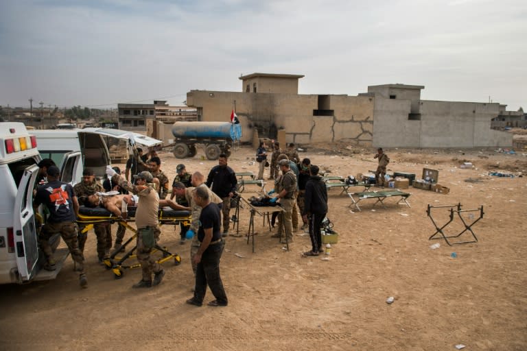 Medics treat a soldier with a gunshot wound at an outdoor field clinic in the Samah neighbourhood of Mosul on November 15, 2016
