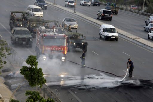 Lebanese civil defence personnel clean the road after Muslim Shiites blocked the highway leading to Beirut airport, May 23, to protest the abduction of 13 Lebanese Shiite men the day before in Syria. The rebel Free Syrian Army denied it was behind the abduction, an incident stoking tensions in neighbouring Lebanon which is divided between pro- and anti-Damascus camps