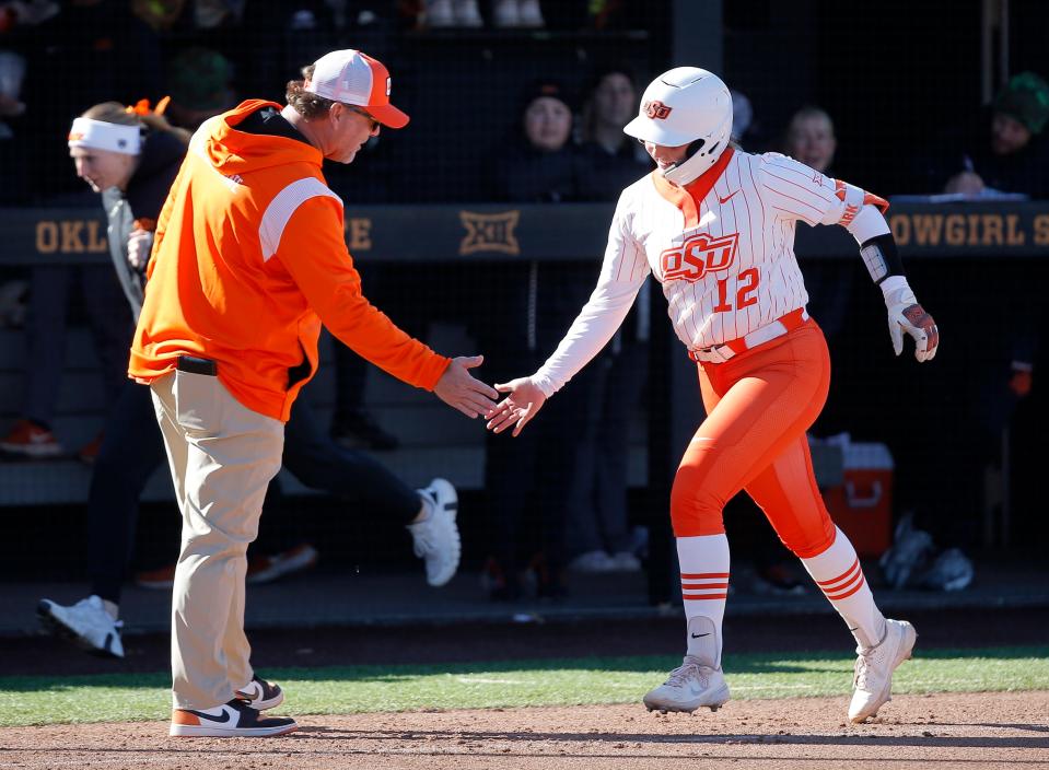 OSU's Micaela Wark celebrates a home run with Cowgirl coach Kenny Gajewski last week against Minnesota.