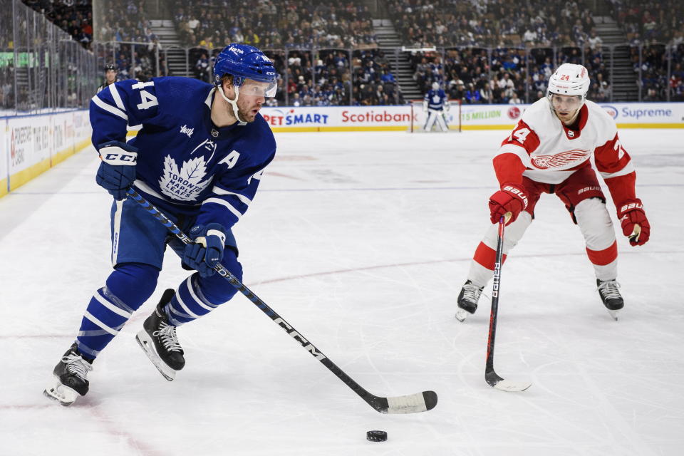 Toronto Maple Leafs defenseman Morgan Rielly (44) is defended by Detroit Red Wings center Pius Suter (24) during the second period of an NHL hockey game in Toronto on Sunday, April 2, 2023. (Christopher Katsarov/The Canadian Press via AP)