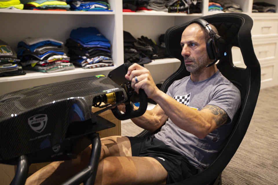 IndyCar driver Tony Kanaan, of Brazil, practices on his racing simulator in his home in Indianapolis, Saturday, March 28, 2020. Kanaan, along with other IndyCar drivers and NASCAR's Jimmie Johnson will compete in the series' inaugural virtual racing event Saturday. (AP Photo/Michael Conroy)