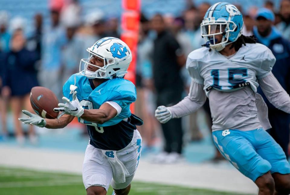 North Carolina wide receiver Tychaun Chapman (0) works to pull in a pass from quarterback Connor Harrell (15) ahead of defensive back Ladaeson Hollins (15) during a scrimmage at the Tar Heels’ open practice on Saturday, March 25, 2023 at Kenan Stadium in Chapel Hill. N.C.