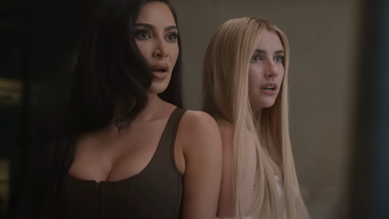 kim kardashian and emma roberts standing shoulder to shoulder with shocked expressions on their faces in a scene for american horror story delicate