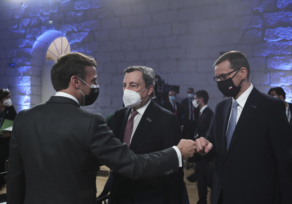 French President Emmanuel Macron, left, fist bumps Poland's Prime Minister Mateusz Morawiecki during the opening ceremony of an EU summit at the Alfandega do Porto Congress Center in Porto, Portugal, Friday, May 7, 2021. European Union leaders are meeting for a summit in Portugal on Friday, sending a signal they see the threat from COVID-19 on their continent as waning amid a quickening vaccine rollout. Their talks hope to repair some of the damage the coronavirus has caused in the bloc, in such areas as welfare and employment. (AP Photo/Luis Vieira, Pool)