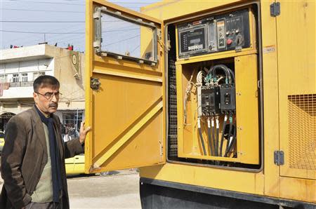 A man stands next to an electricity generator set up to power a market in the town of Amuda, December 7, 2013. Picture taken December 7, 2013. REUTERS/Rodi Said