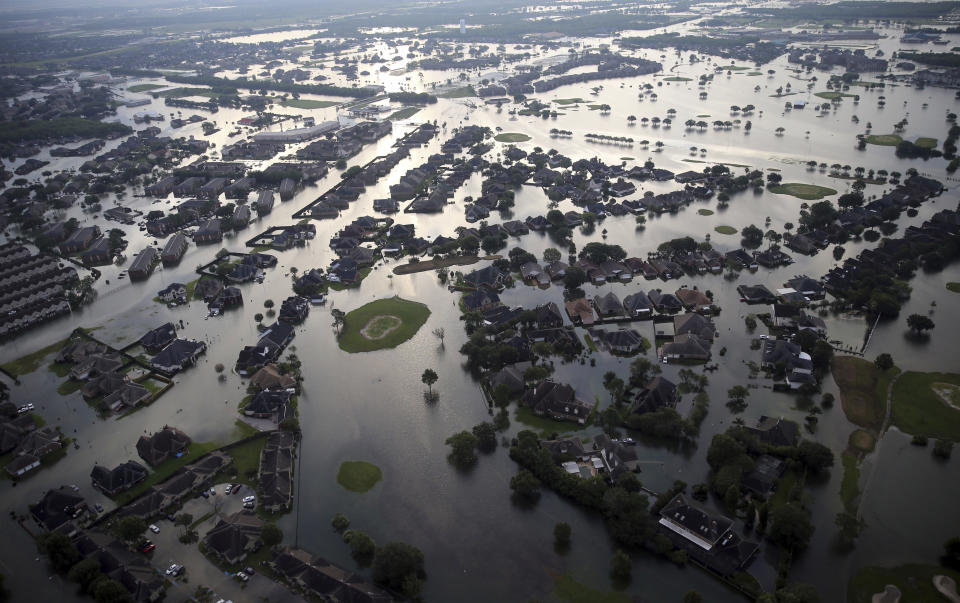 FILE - In this Aug. 31, 2017, file photo, floodwaters from Tropical Storm Harvey surround homes in Port Arthur, Texas. Many Texas families are still struggling to recover from Hurricane Harvey, a year after it caused widespread damage and flooding along the Gulf Coast and in and around Houston. But daily life has mostly returned to normal in many of the hardest hit communities. (AP Photo/Gerald Herbert, File)