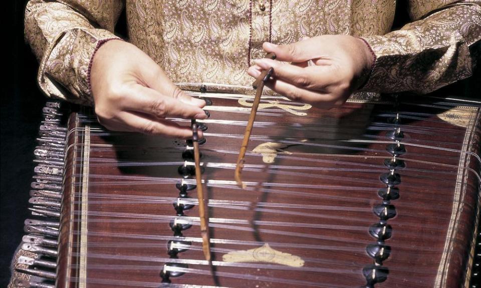 A closeup of Shivkumar Sharma playing the santoor. It is an ancient folk instrument with 100 strings and is struck with small mallets rather than plucked.