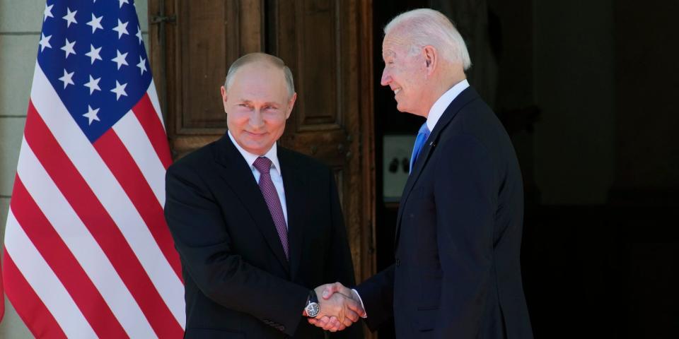 Vladimir Putin and Joe Biden smiling and shaking hands.