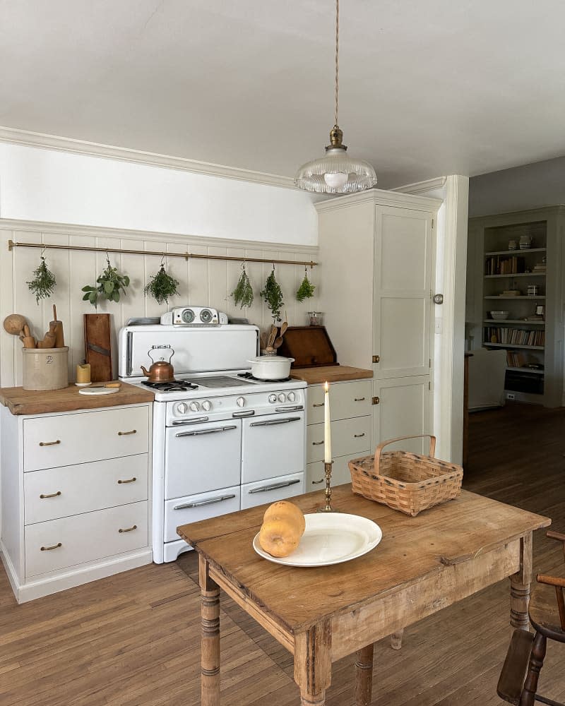 Vintage stove in neutral kitchen with butcher block countertops and small island.