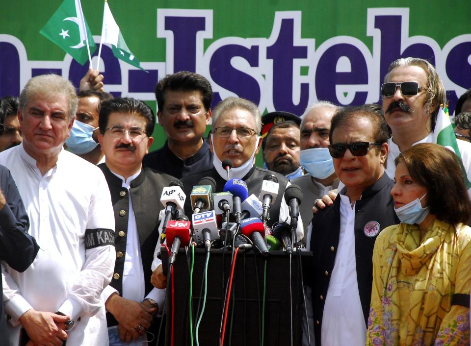 Pakistan's President Arif Alvi, center, stands with parliamentarians while addressing participants at a rally to show solidarity with Kashmiri people on the eve of the first anniversary of India's decision to revoke the disputed region's semi-autonomy, in Islamabad, Pakistan, Wednesday, Aug. 5, 2020. Last year on Aug. 5, India's Hindu-nationalist-led government of Prime Minister Narendra Modi stripped Jammu and Kashmir's statehood, scrapped its separate constitution and removed inherited protections on land and jobs. (AP Photo/A.H. Chuadary)