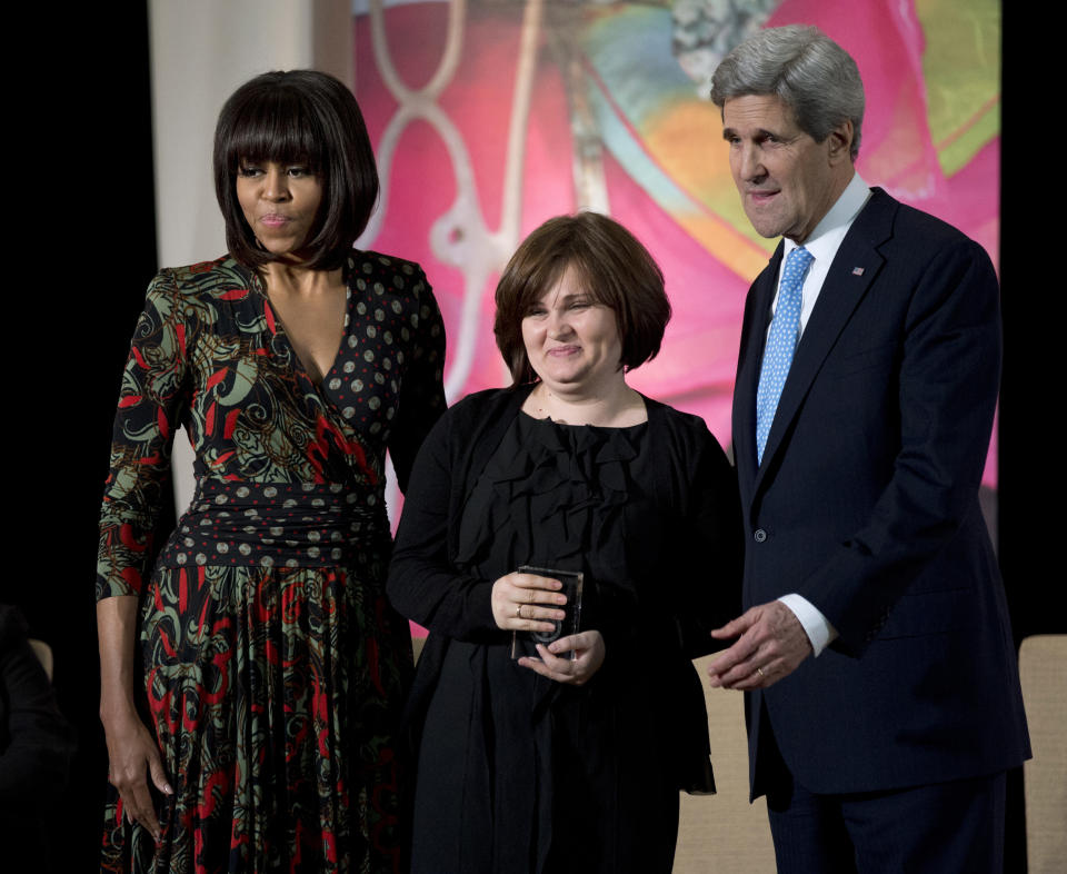 FILE - Then First lady Michelle Obama, left, and then Secretary of State John Kerry, right, honor Russian human rights activist, journalist Elena Milashina, with a Secretary of State's International Women of Courage Award during a ceremony at the State Department in Washington, Friday, March 8, 2013. Unidentified masked assailants in the Russian province of Chechnya have attacked and beaten a journalist and a lawyer. Novaya Gazeta journalist Elena Milashina and lawyer Alexander Nemov had just arrived in Chechnya. Outside the airport, they were beaten by several masked assailants. (AP Photo/Manuel Balce Ceneta, File)