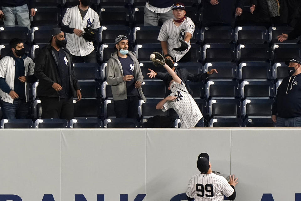 New York Yankees right fielder Aaron Judge (99) watches a fan grab a home run hit by Baltimore Orioles Rio Ruiz during the ninth inning of a baseball game, Tuesday, April 6, 2021, at Yankee Stadium in New York. (AP Photo/Kathy Willens)