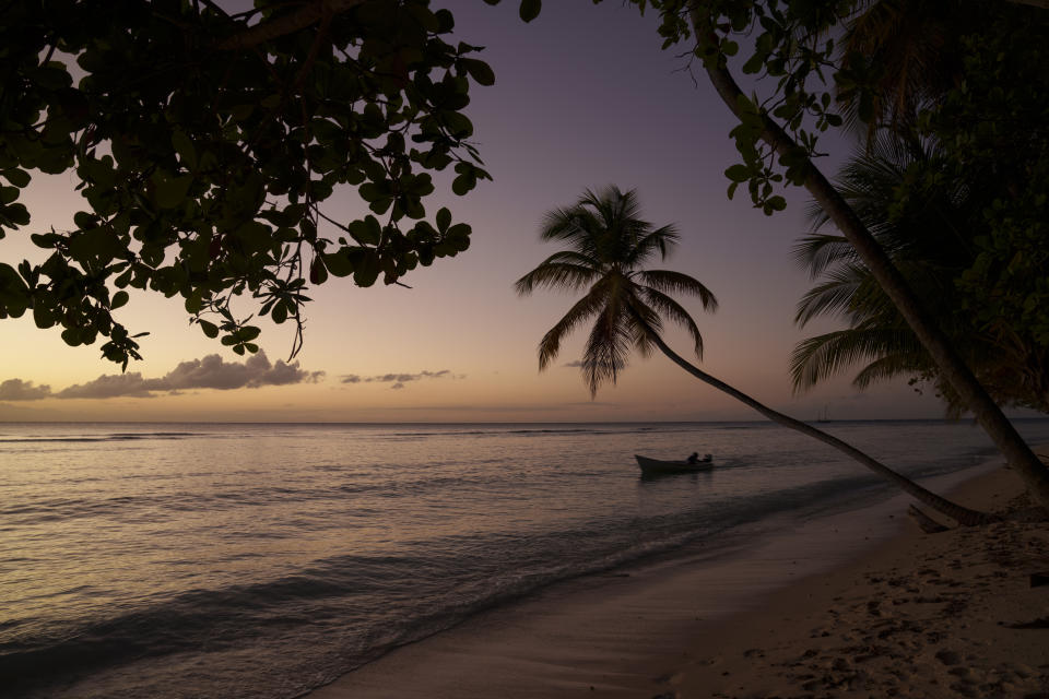 Un barco navega al atardecer por la orilla en una playa de la isla de Tobago, en Trinidad y Tobago, el 23 de enero de 2022. (AP Foto/Felipe Dana)