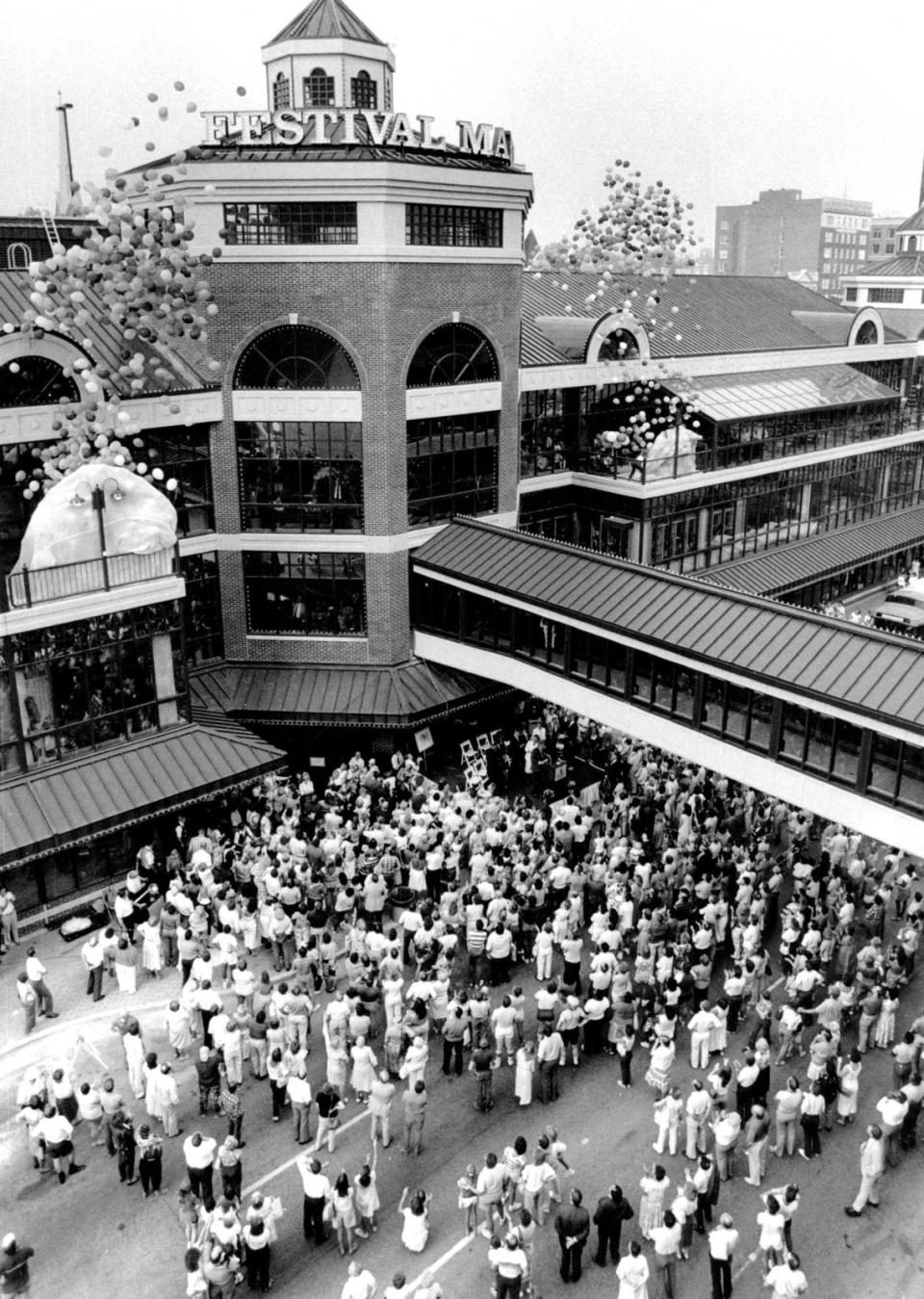 A large crowd was on hand as hundreds of balloons were released to signal the grand opening the Festival Market on July 25, 1986. The grand opening for $16 million development at West Main Street and North Broadway kicked off 10 days of festivities that allowed the public to become acquainted with the shops and restaurants located inside the 3-story marketplace. About 42 of the market’s 72 shops and restaurants were open. The development failed to generate sustained profit and the complex was sold for $600,000 in 1994 in an auction. Festival Market was rebranded in 1999 as Triangle Center, consisting primarily of offices with a few retail and restaurant entries.