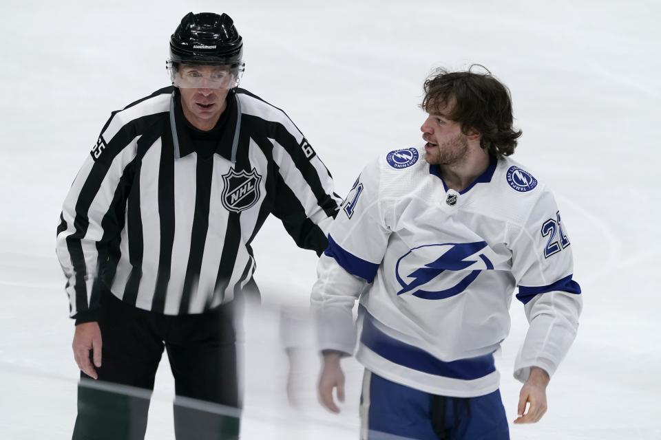 Linesmen Pierre Racicot, left, escorts Tampa Bay Lightning's Brayden Point (21) to the penalty box after Point and Dallas Stars' Andrew Cogliano fought in the third period of an NHL hockey game in Dallas, Tuesday, March 2, 2021. (AP Photo/Tony Gutierrez)