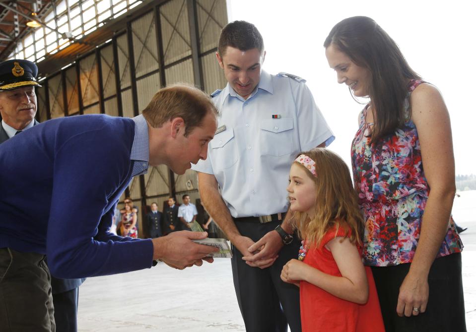 Britain's Prince William accepts a book from Maia Hunt, 6, while watched by her parents Squadron Leader Steve Hunt and his wife Kate in Auckland