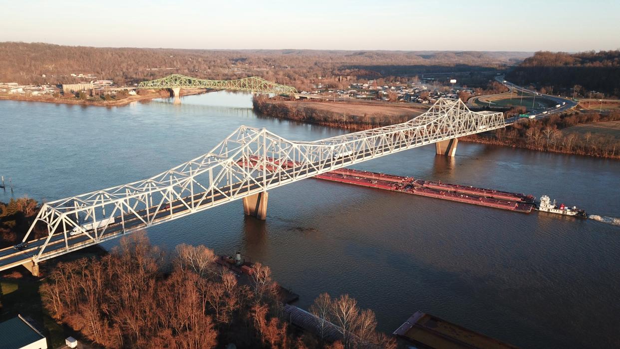 A barge pushes goods under the Silver Memorial Bridge that spans the Ohio River between Gallipolis, Ohio and Henderson, West Virginia. The bridge was completed in 1969 as a replacement for the collapsed Silver Bridge, although it is located about 1 mile downstream of the original. The smaller green bridge is the Point Pleasant-Henderson Bridge over the Kanawha River, connecting Point Pleasant and Henderson, West Virginia, at the point where the Kanawha empties into the Ohio River. Photographed January 11, 2022.