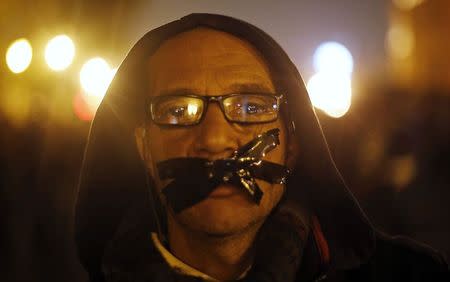 An anti-Mubarak protester stands with his mouth taped, during a protest against the government and military, after former Egyptian President Hosni Mubarak's verdict, around a statue of Egypt's former Army Chief of Staff Abdel Moneim Riad near Tahrir square in downtown Cairo November 29, 2014. REUTERS/Amr Abdallah Dalsh