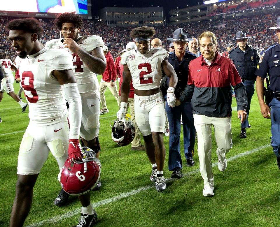 Alabama defensive back Caleb Downs and coach Nick Saban grasp hands as they walk off the field after Saturday's dramatic win against Auburn.