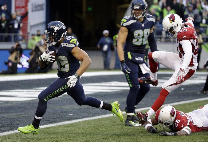 Seattle Seahawks' Doug Baldwin runs in for a touchdown on a pass reception as Arizona Cardinals' Brandon Williams (26) and Justin Bethel (28) follow in the second half of an NFL football game, Saturday, Dec. 24, 2016, in Seattle. (AP Photo/Ted S. Warren)