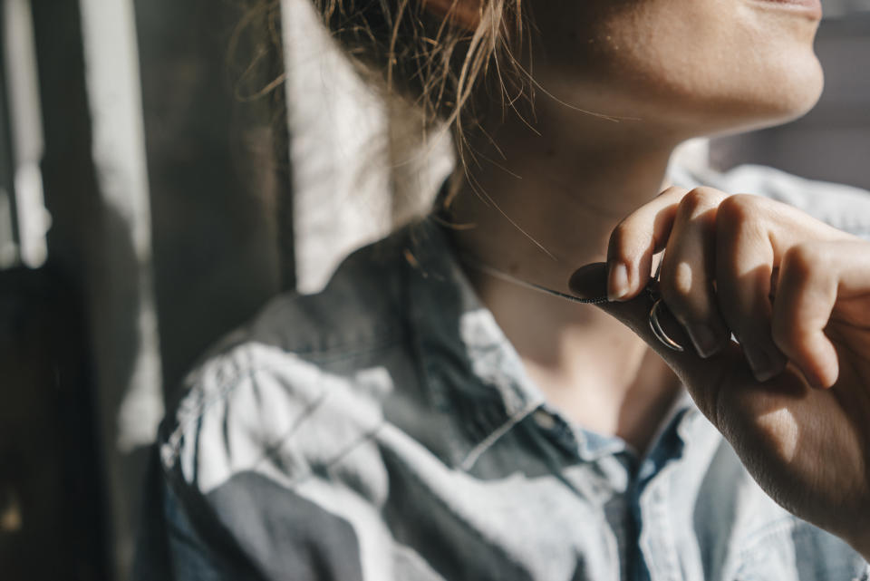 Young woman holding pendant of her necklace