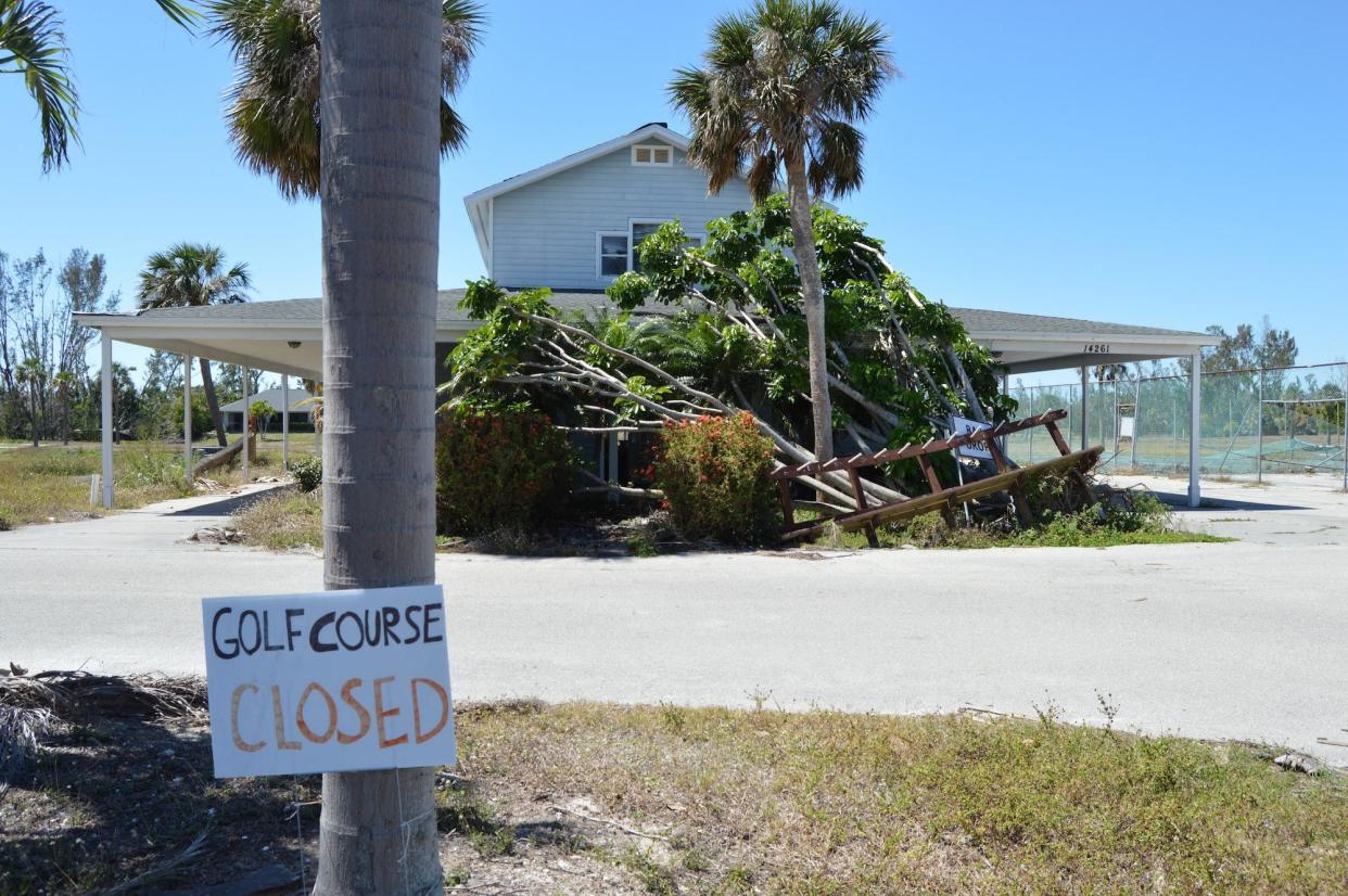 Nearly six months after Hurricane Ian, a tree is draped across the front of the Alden Pines Golf Course clubhouse.