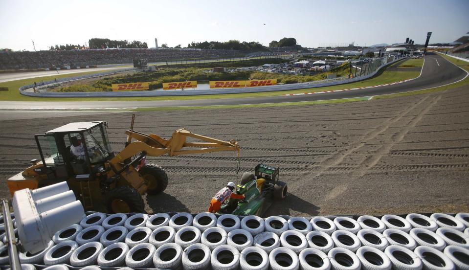 Track marshalls remove the car of Caterham Formula One driver Giedo van der Garde of Netherlands after he crashed, during the Japanese F1 Grand Prix at the Suzuka circuit October 13, 2013. REUTERS/Issei Kato (JAPAN - Tags: SPORT MOTORSPORT F1)