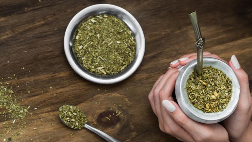 Manos de una mujer sostienen un mate con yerba.