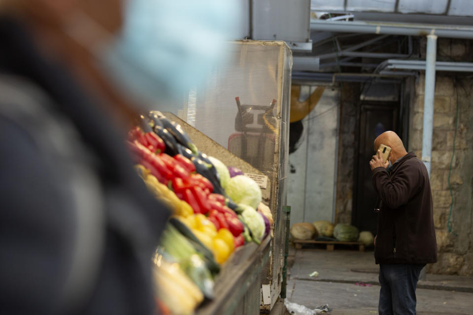 A man in a protective mask passes another man talking on his mobile phone at the Mahane Yehuda market in Jerusalem, Wednesday, Dec. 23, 2020. In the early days of the pandemic, a panicked Israel began using a mass surveillance tool on its own people, tracking civilians’ mobile phones to halt the spread of the coronavirus. But months later, the tool’s effectiveness is being called into question and critics say its use has come at an immeasurable cost to the country’s democratic principles. (AP Photo/Maya Alleruzzo)