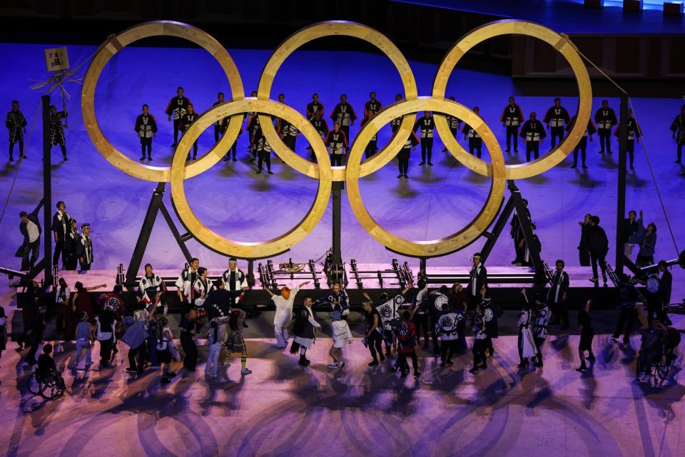 Performers surround the Olympic rings on stage