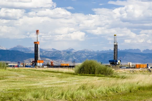 Drilling rigs against a backdrop of mountains