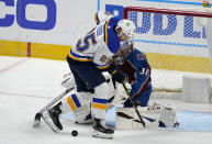 St. Louis Blues center Jordan Kyrou, front, struggles to direct a shot on Colorado Avalanche goaltender Philipp Grubauer during the first period of an NHL hockey game Wednesday, Jan. 13, 2021, in Denver. (AP Photo/David Zalubowski)