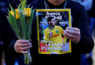 A man holds a sports magazine and yellow tulips as fans gather in Nantes' city center after news that newly-signed Cardiff City soccer player Emiliano Sala was missing after the light aircraft he was travelling in disappeared between France and England the previous evening, according to France's civil aviation authority, France, January 22, 2019. REUTERS/Stephane Mahe