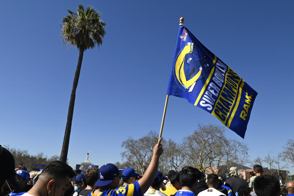 A fan waves a flag during the Los Angeles Rams' victory parade in Los Angeles, Wednesday, Feb. 16, 2022, following the Rams' win Sunday over the Cincinnati Bengals in the NFL Super Bowl 56 football game. (AP Photo/Kyusung Gong)