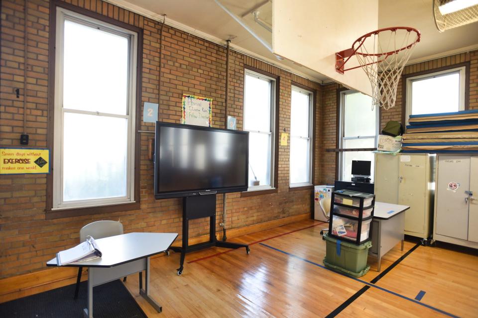 Students can’t shoot a basketball with much arc because it would bounce off the low ceilings of the gymnasium at Paterson’s School 19. A desk, smart board, drawers, white board, boxes and cabinets stacked with mats are crammed into the corner, spilling over the court’s boundary lines.