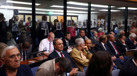 People hold up portraits of those who disappeared during Argentina's military dictatorship, behind former Navy officers on trial for their role during the 1976-1983 dictatorship, in Buenos Aires, November 29, 2017. REUTERS/Marcos Brindicci