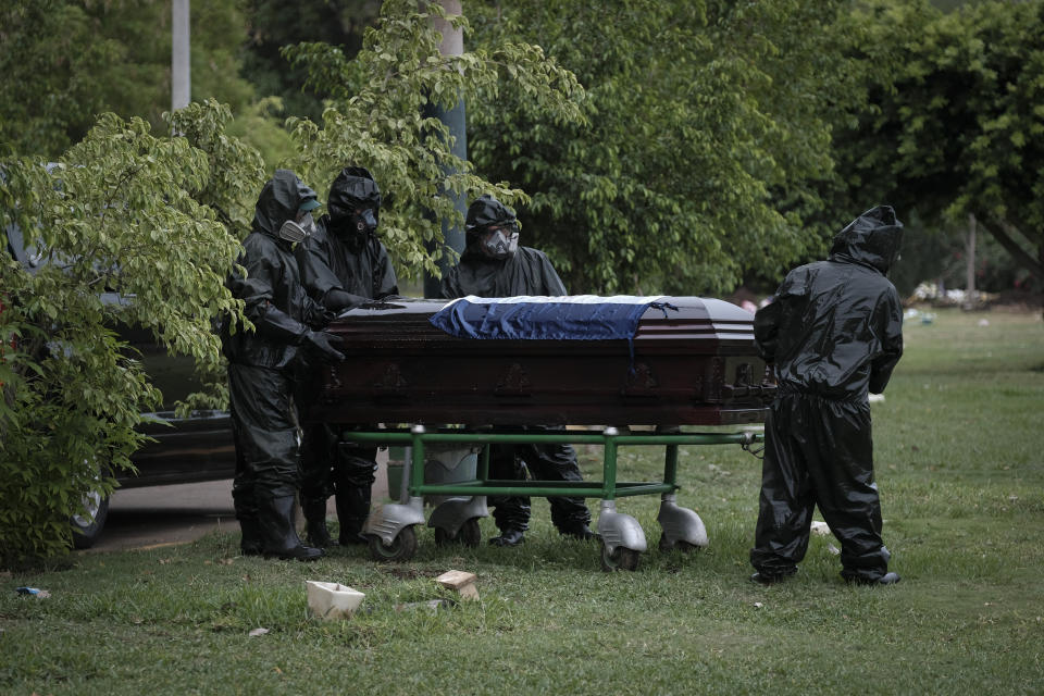 Workers in full protection gear against the spread of the new coronavirus move the coffin with the body of journalist Carlos Bermudez for burial at the Jardines del Recuerdo cemetery in Managua, Nicaragua, Wednesday, May 27, 2020. Family members said that Bermudez died from COVID-19, even as President Daniel Ortega's government has gone from denying the disease's presence in the country to actively trying to conceal its spread. (AP Photo/Alfredo Zuniga)