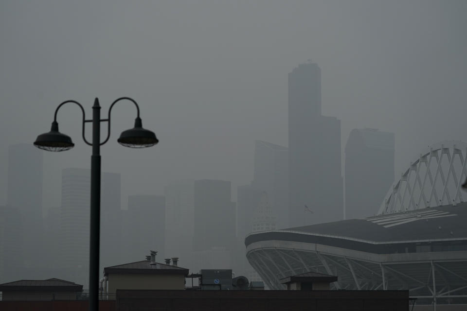 FILE - In this Sept. 14, 2020, file photo, downtown Seattle is barely visible through wildfire smoke, Wednesday, Oct. 14, 2020, near CenturyLink Field, right, as viewed from an upper deck of T-Mobile Park, home of the Seattle Mariners baseball team. Wildfires churning out dense plumes of smoke as they scorch huge swaths of the U.S. West Coast have exposed millions of people to hazardous pollution levels, causing emergency room visits to spike and potentially thousands of deaths among the elderly and infirm, according to an Associated Press analysis of pollution data and interviews with physicians, health authorities and researchers. (AP Photo/Ted S. Warren, File)
