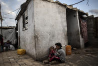 Palestinian children eat while sitting on the ground in their house in a slum on the outskirts of Khan Younis Refugee Camp, in the southern Gaza Strip, Wednesday, Nov. 25, 2020. Israel's blockade of the Hamas-ruled Gaza Strip has cost the seaside territory as much as $16.7 billion in economic losses and caused its poverty and unemployment rates to skyrocket, a U.N. report said Wednesday, as it called on Israel to lift the 13-year closure. (AP Photo/Khalil Hamra)