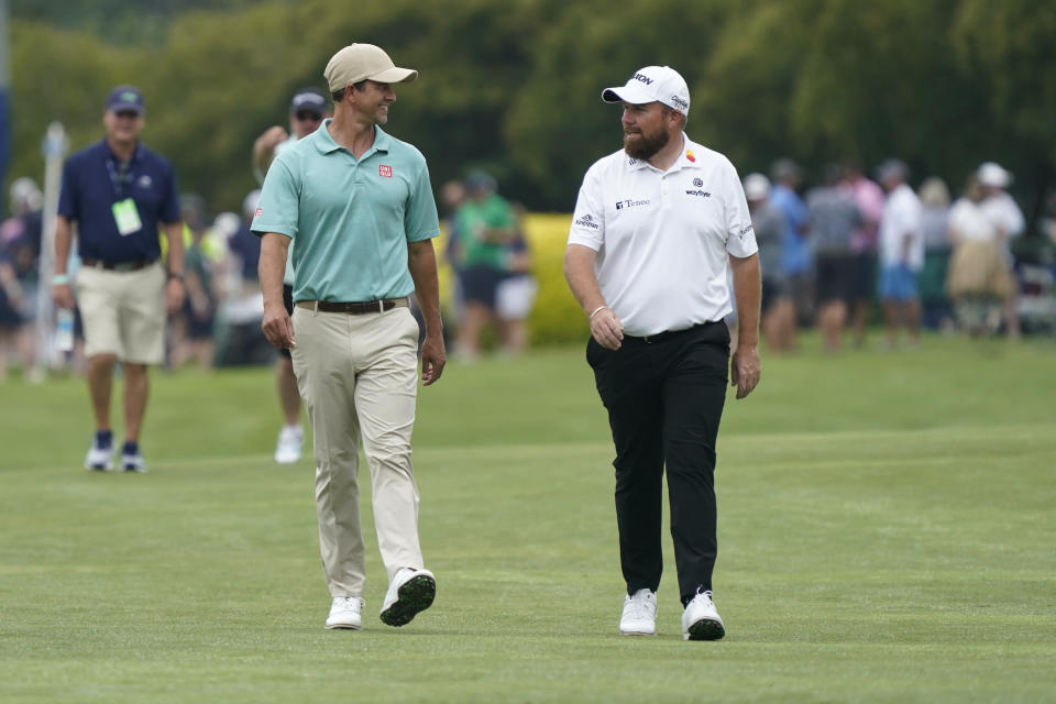 Adam Scott, of Australia, left, talks with Shane Lowry, right, as they walk down the first fairway during the second round of the Wyndham Championship golf tournament in Greensboro, N.C., Friday, Aug. 4, 2023. (AP Photo/Chuck Burton)