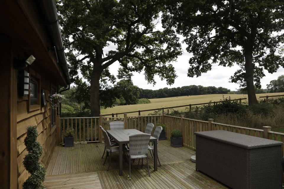 An outdoor table stands on decking outside a holiday home with a view of the surrounding countryside at the Edgeley Holiday Park in Farley Green, near Guildford, south west of London, Wednesday, July 22, 2020. With all schools now closed, Friday would normally be the busiest departure day of the year for London’s Gatwick Airport with families heading off to the sun-soaked beaches in southern Europe. Not this year as the coronavirus pandemic has meant many have opted against making their annual summer migration to countries like Spain and Greece. Gatwick would in any normal year be expecting to fly some 85,000 holidaymakers on Friday alone. It expects less than 10,000 passenger departures on Friday. (AP Photo/Matt Dunham)