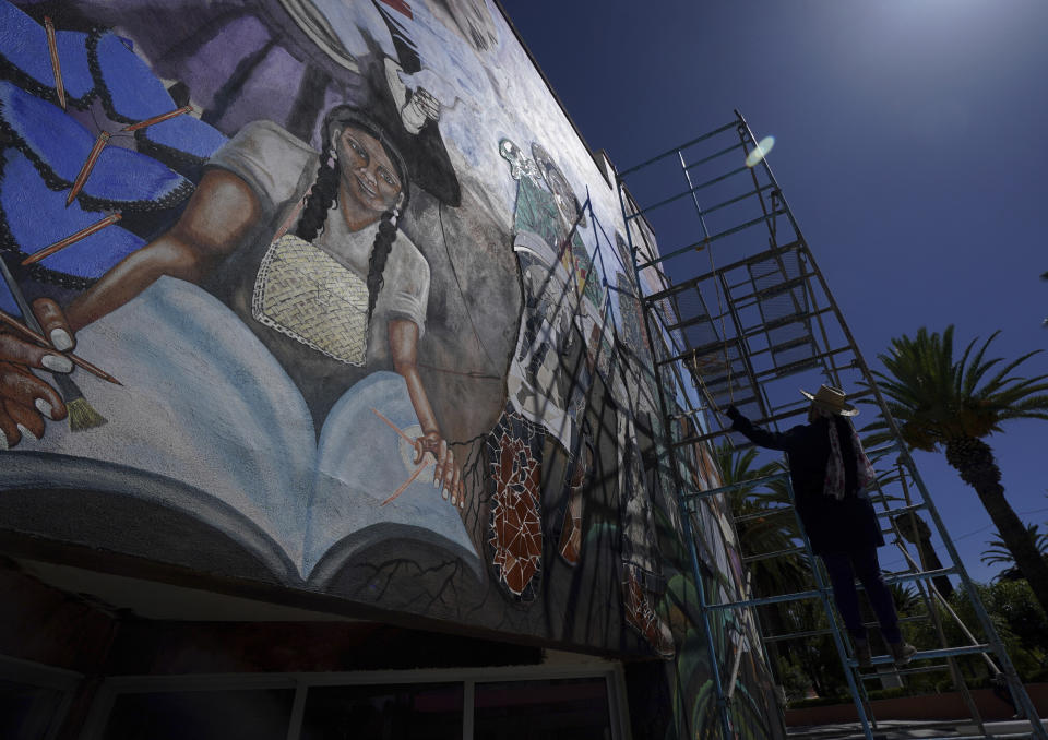 Mexican mural artist Yanet Calderon paints on the facade of a municipal building in San Salvador, Mexico, Saturday, July 30, 2022. Calderon is part of a group of artists helping to revive muralism, a movement that put Mexico at the vanguard of art a century ago. (AP Photo/Fernando Llano)