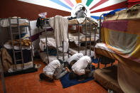 Asylum-seekers pray next to their beds at the Modern Christian Mission Church in Fuerteventura, one of the Canary Islands, Spain, on Saturday, Aug. 22, 2020. The Modern Christian Mission is the main shelter for rescued migrants on the island of Fuerteventura. (AP Photo/Emilio Morenatti)