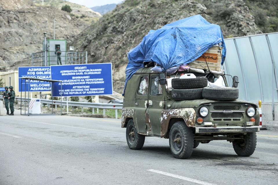 FILE -Sergey Astsetryan, an ethnic Armenian resident of Nagorno-Karabakh, drives his Soviet-made vehicle past Azerbaijani border guard servicemen after been checked at the Lachin checkpoint on the way from Nagorno-Karabakh to Armenia, in Azerbaijan, Sunday, Oct. 1, 2023. A human rights organization representing ethnic Armenians has submitted evidence to the International Criminal Court arguing that Azerbaijan is committing an ongoing genocide against them. (AP Photo/Aziz Karimov, File)